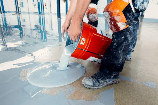 Construction workers applying epoxy flooring system with a self-leveling epoxy compound